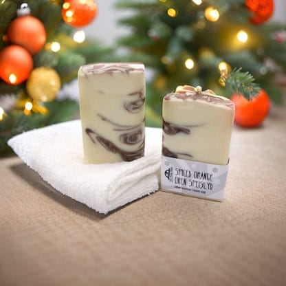 Two bars of brown and white soap on a table in front of a Christmas tree