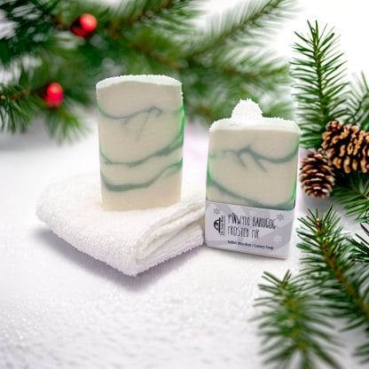 Two bars of handmade soap on a background of fir trees