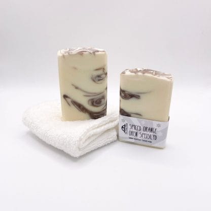 Two bars of brown and white handmade soap and a white facecloth