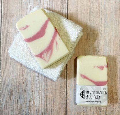 Two bars of pink and white soap on brown planks in the background