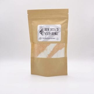 A resealable kraft bag with a window showing the orange and white bath sprinkles inside